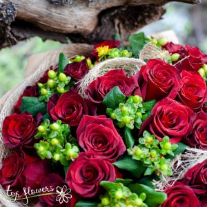 Round bouquet of 31 red roses with greenery