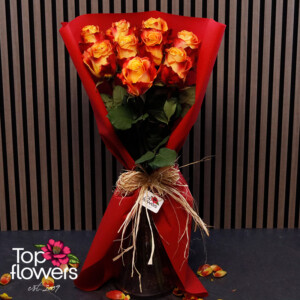 Fiery roses in red wrapping with a natural ribbon
